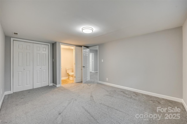 unfurnished bedroom featuring ensuite bath, a closet, and carpet floors