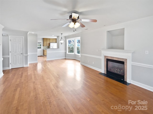 unfurnished living room featuring ceiling fan, light wood-type flooring, a tile fireplace, and crown molding