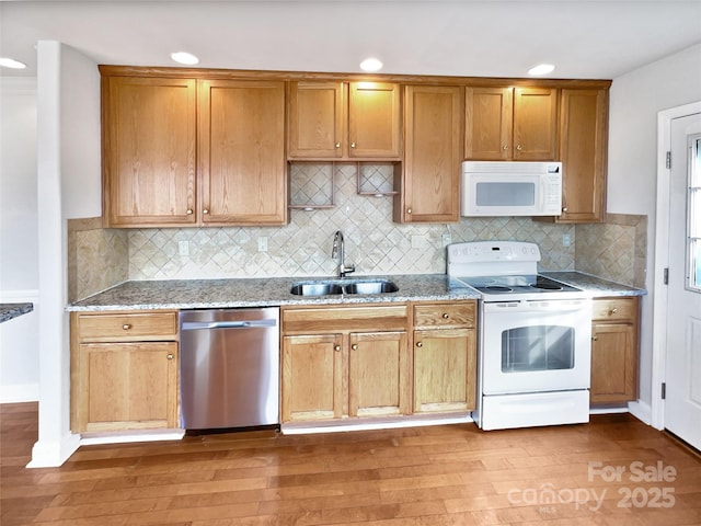 kitchen featuring light stone countertops, sink, white appliances, and hardwood / wood-style floors