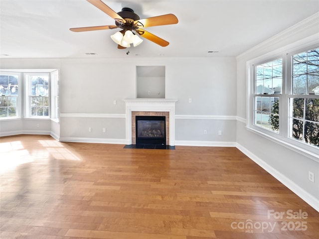 unfurnished living room featuring a healthy amount of sunlight, light wood-type flooring, a fireplace, and crown molding