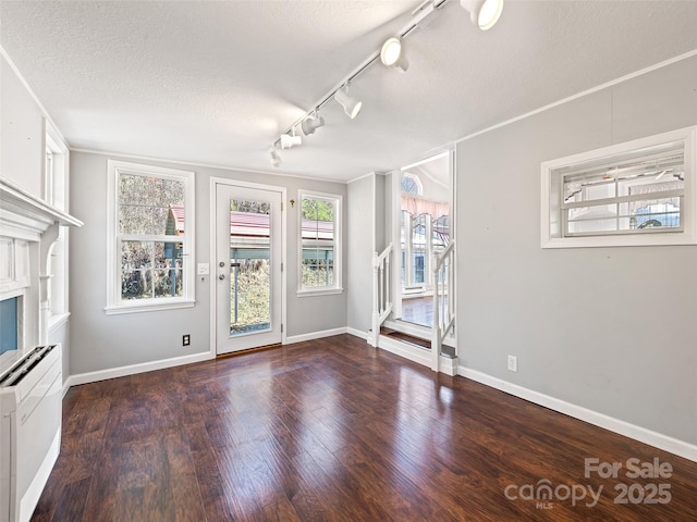 unfurnished living room featuring a fireplace, a textured ceiling, dark hardwood / wood-style floors, and ornamental molding