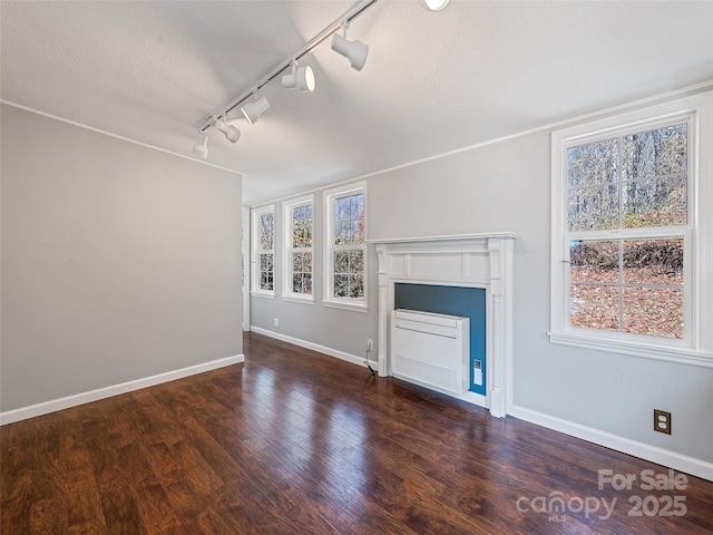 unfurnished living room featuring track lighting, a textured ceiling, and dark hardwood / wood-style flooring