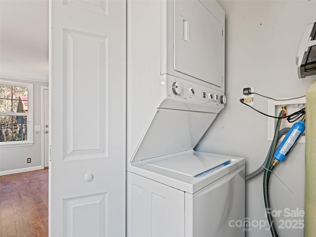 laundry room featuring dark hardwood / wood-style floors and stacked washer and dryer