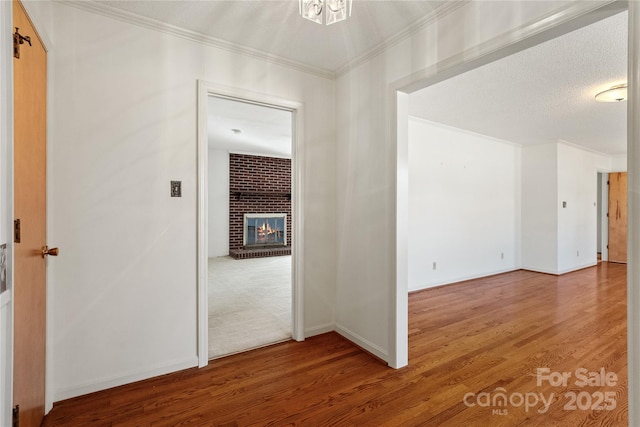 hallway with a textured ceiling, crown molding, and hardwood / wood-style flooring