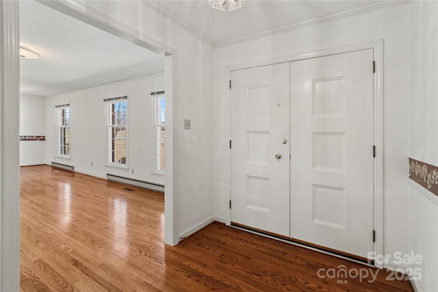 entrance foyer featuring baseboard heating, a textured ceiling, ornamental molding, and wood-type flooring