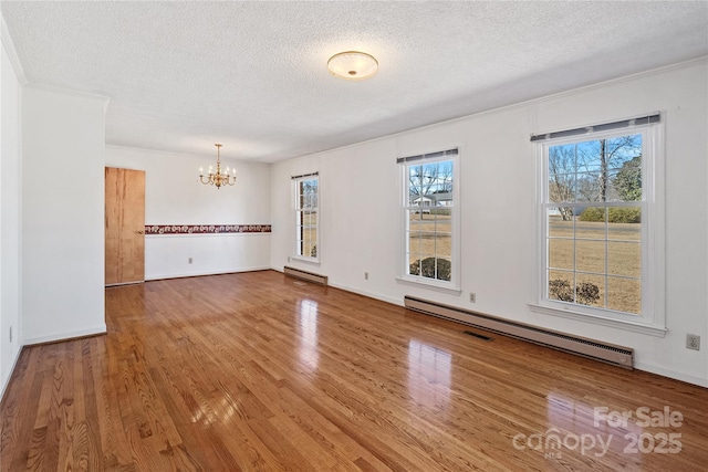 spare room featuring a textured ceiling, a baseboard heating unit, and a notable chandelier