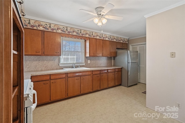 kitchen featuring stainless steel fridge, ceiling fan, stove, ornamental molding, and sink