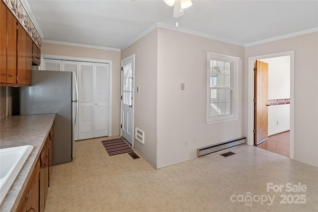 kitchen featuring a baseboard heating unit, ceiling fan, stainless steel refrigerator, crown molding, and sink