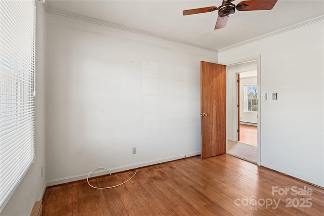 spare room featuring ceiling fan, ornamental molding, baseboard heating, and hardwood / wood-style floors