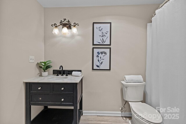 bathroom with baseboards, vanity, toilet, and wood finished floors