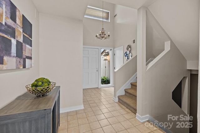 entrance foyer featuring a notable chandelier, light tile patterned floors, visible vents, baseboards, and stairs