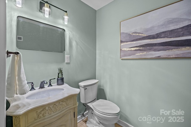 bathroom featuring baseboards, vanity, and toilet