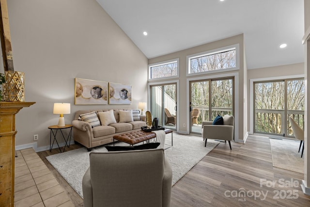 living room with high vaulted ceiling, recessed lighting, baseboards, and light wood finished floors