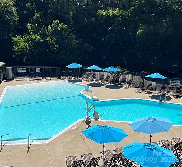 community pool with a patio area and fence