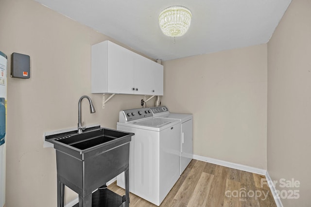 laundry room with cabinet space, light wood finished floors, baseboards, independent washer and dryer, and a sink