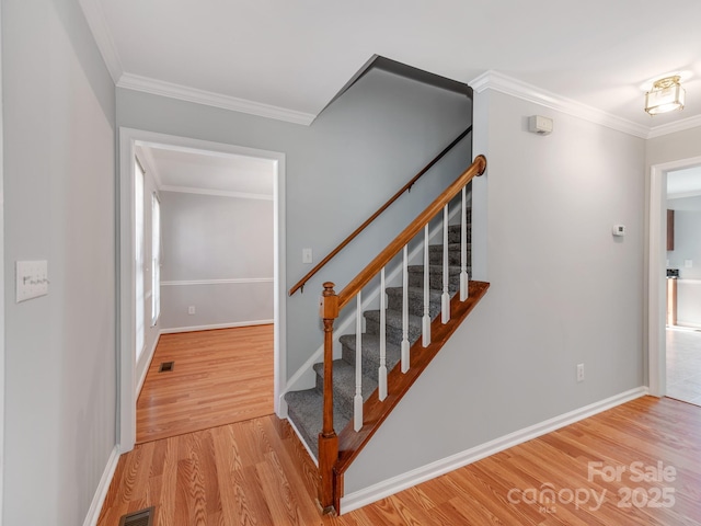 stairway with crown molding and wood-type flooring