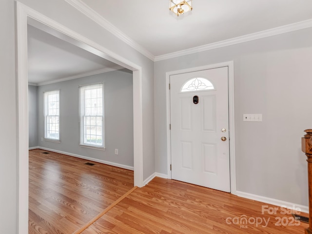 foyer entrance with ornamental molding and light hardwood / wood-style flooring