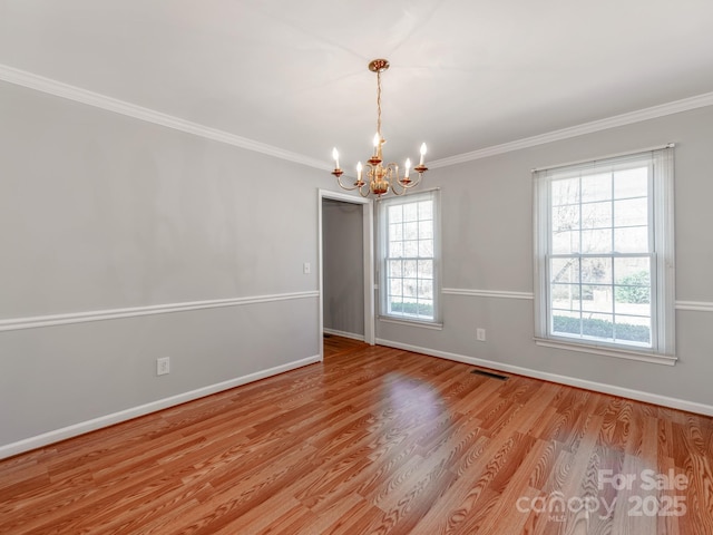 spare room featuring light wood-type flooring, a chandelier, and ornamental molding