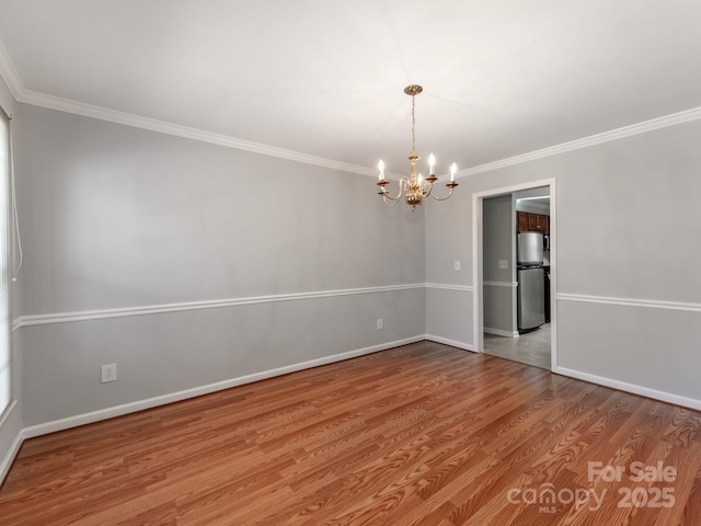 spare room with light hardwood / wood-style floors, crown molding, and an inviting chandelier