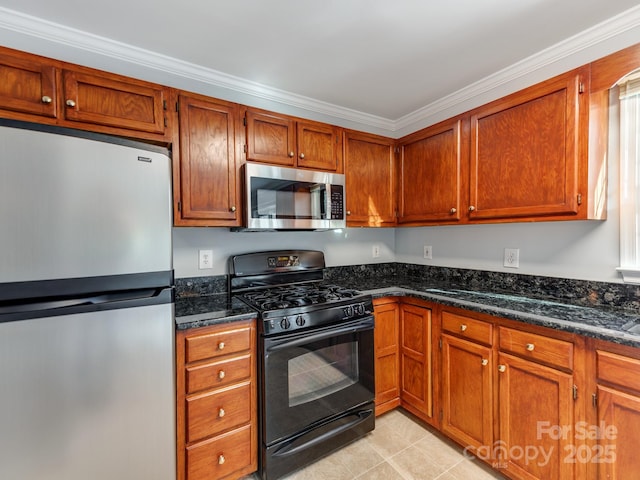 kitchen with light tile patterned floors, appliances with stainless steel finishes, dark stone counters, and ornamental molding