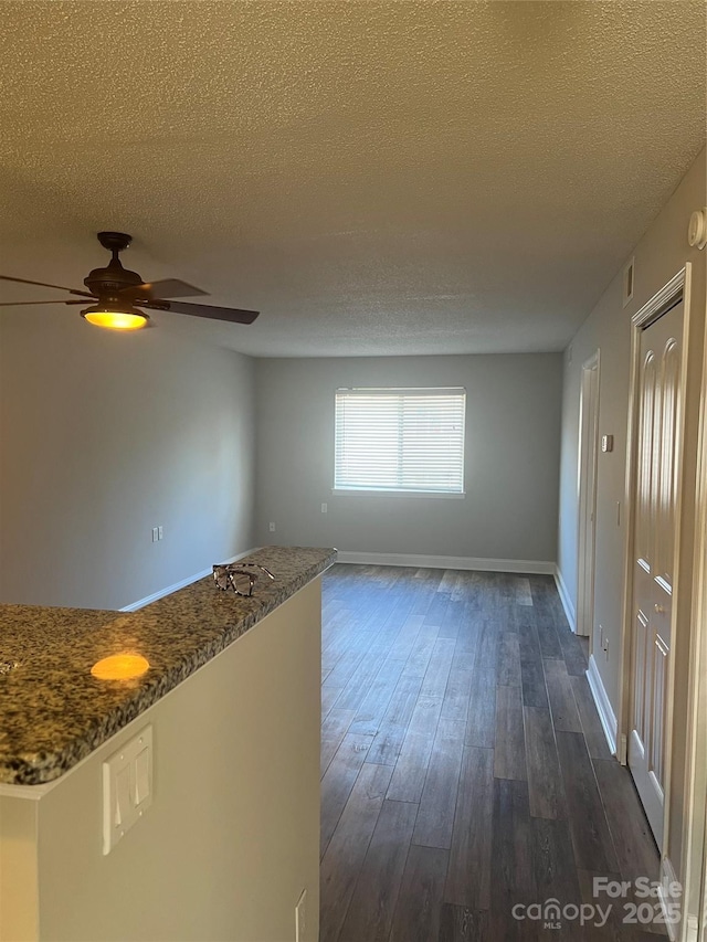 spare room featuring ceiling fan, dark wood-type flooring, and a textured ceiling