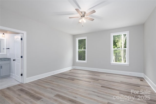 spare room featuring plenty of natural light, ceiling fan, and light wood-type flooring