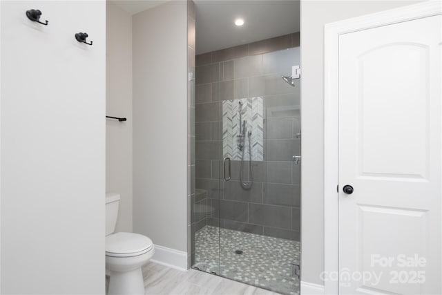 bathroom featuring a shower with shower door and toilet