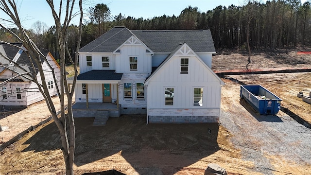 view of front facade with board and batten siding, a shingled roof, and a forest view