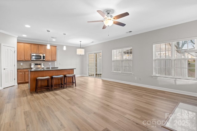 kitchen with decorative light fixtures, crown molding, stainless steel appliances, and a breakfast bar area