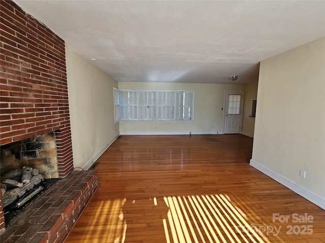 unfurnished living room with dark wood-type flooring and a fireplace