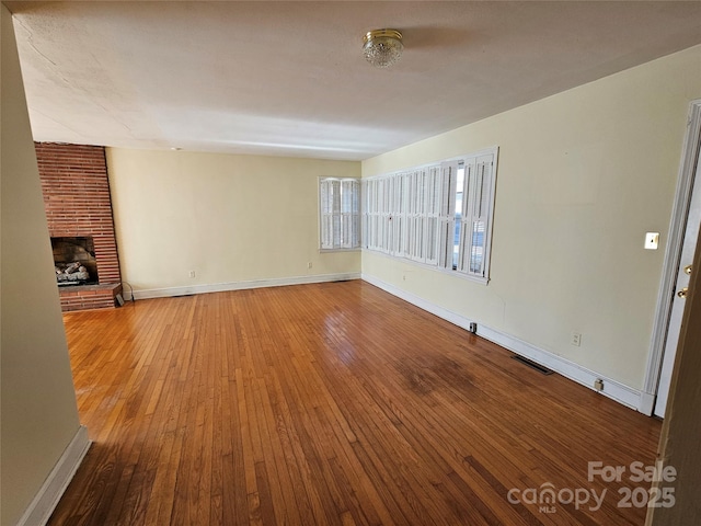 unfurnished living room featuring a brick fireplace and wood-type flooring