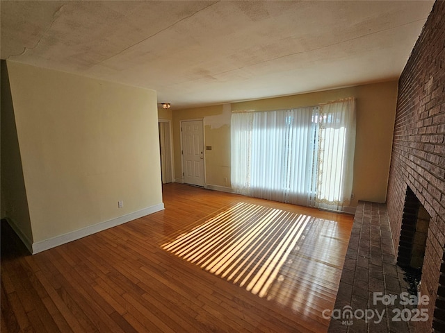 unfurnished living room with a brick fireplace and wood-type flooring