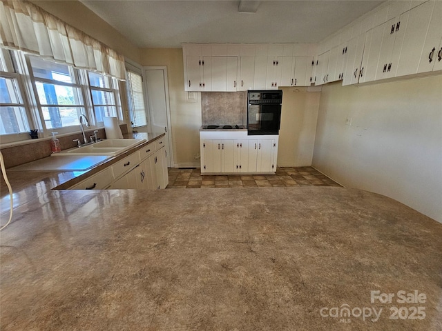 kitchen featuring white cabinetry, sink, kitchen peninsula, and black appliances