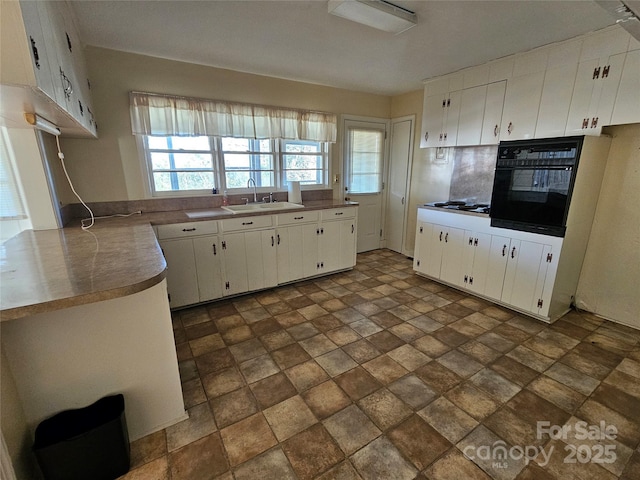 kitchen featuring white gas stovetop, sink, white cabinets, and oven