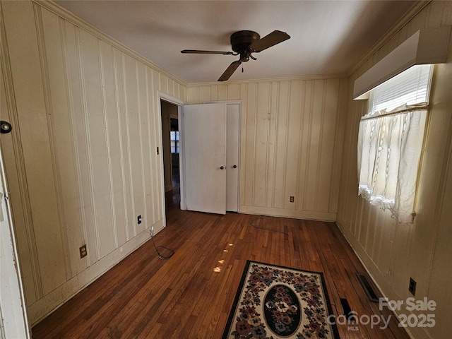 empty room with ceiling fan, dark hardwood / wood-style floors, and crown molding