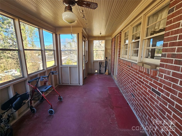 unfurnished sunroom with ceiling fan, wooden ceiling, and plenty of natural light