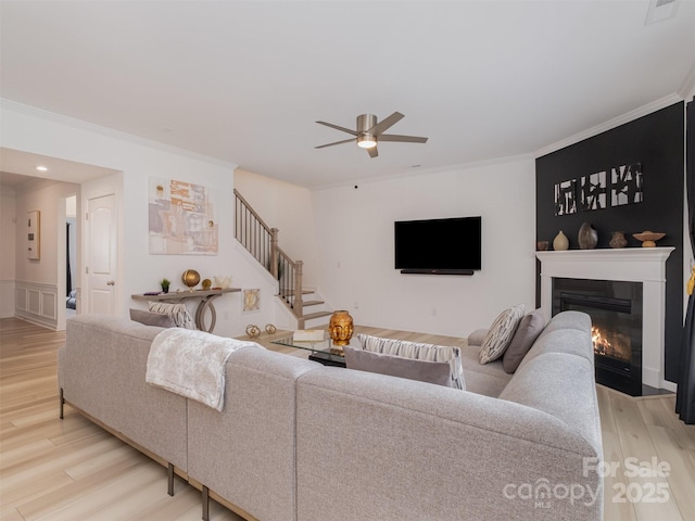 living room featuring ceiling fan, light wood-type flooring, and ornamental molding