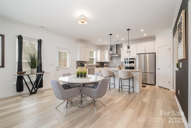 dining room featuring crown molding and light hardwood / wood-style flooring