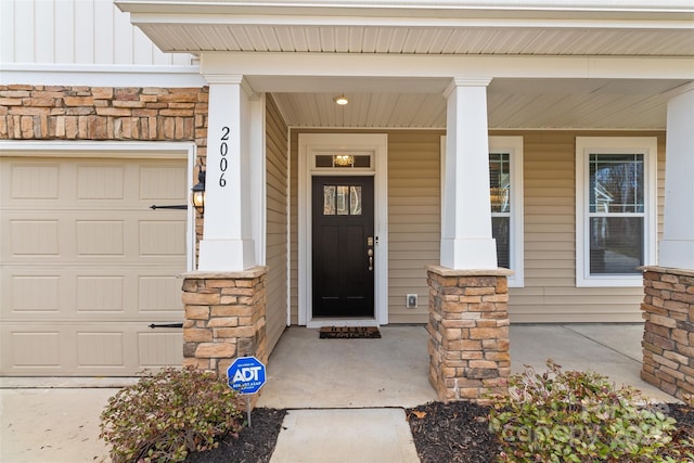 view of exterior entry featuring a garage and covered porch