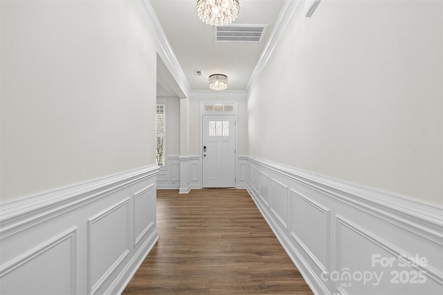 doorway featuring ornamental molding, dark hardwood / wood-style floors, and an inviting chandelier