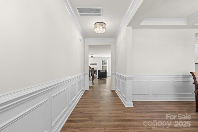 hall featuring dark hardwood / wood-style flooring, crown molding, and a chandelier