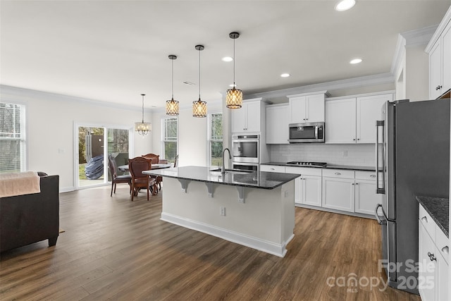 kitchen with sink, appliances with stainless steel finishes, a kitchen island with sink, hanging light fixtures, and white cabinets