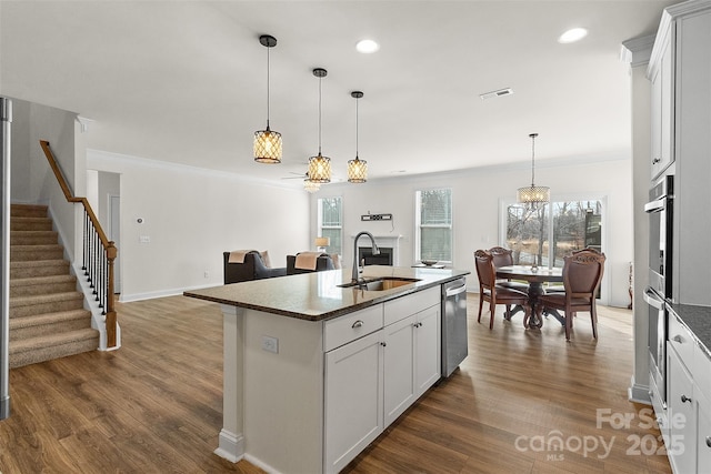 kitchen with white cabinetry, an island with sink, dishwasher, and sink