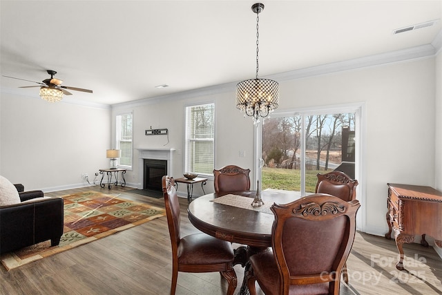 dining room featuring ornamental molding, ceiling fan with notable chandelier, and light hardwood / wood-style flooring