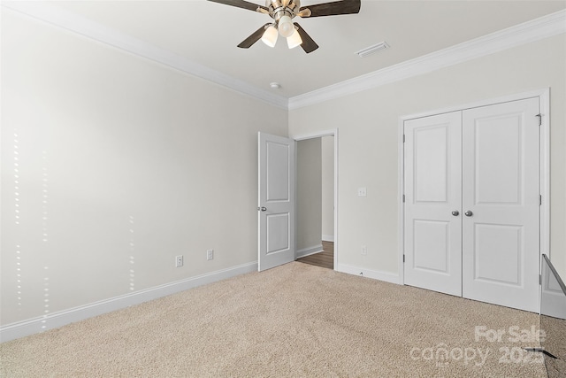 unfurnished bedroom with crown molding, carpet flooring, ceiling fan, and a closet