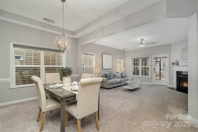 dining area with ceiling fan with notable chandelier and light colored carpet