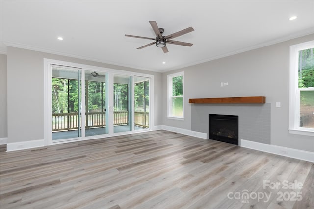 unfurnished living room with light wood-type flooring, crown molding, and plenty of natural light