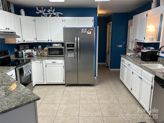 kitchen with white cabinetry, dark stone countertops, light tile patterned floors, and stainless steel appliances