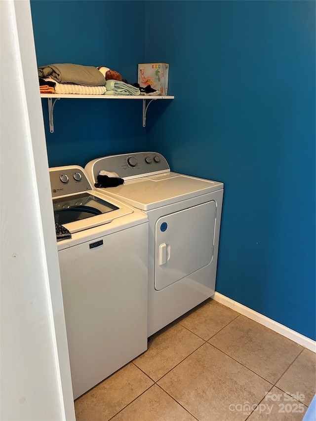 clothes washing area with washing machine and dryer and light tile patterned floors