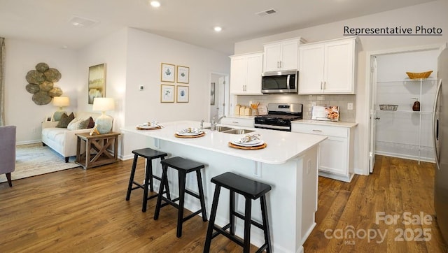 kitchen featuring a center island with sink, appliances with stainless steel finishes, white cabinets, and sink